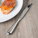 A plate of meat and a Oneida Baguette steak knife on it.