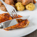 A Oneida Baguette stainless steel steak knife and fork on a plate with meat and potatoes.