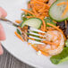 A Oneida Baguette stainless steel salad fork cutting a cucumber slice.