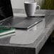 A laptop and a white mug on a clear ES Robbins desk pad.