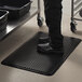 A person standing on a black ES Robbins anti-fatigue floor mat.