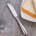 A plate of bread and a Oneida Baguette stainless steel butter knife.