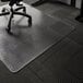 A black office chair with wheels on an ES Robbins clear vinyl chair mat over carpet.