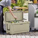 A man putting a beer bottle into a CaterGator tan outdoor cooler.