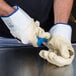 A person wearing yellow rubber oyster shucking gloves holding a knife.