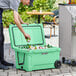 A man putting a can into a CaterGator seafoam outdoor cooler.