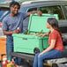 A man and woman sitting on a CaterGator Seafoam cooler full of bottles.