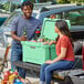 A man and woman sitting on the back of a truck with a CaterGator Seafoam cooler full of beer.