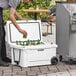 A man opening a white CaterGator cooler to put a can inside.