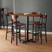 A Lancaster Table & Seating bar height table with a live edge and wooden chairs.