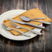 A table with a plate of silverware including a Walco Fieldstone Finish spoon and knife.