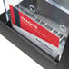 A black Deflecto 3-tier literature holder with a business card in a plastic box.
