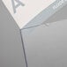 A white and grey paper with a blue letter a in a Deflecto clear slanted sign holder.