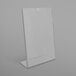 A clear plastic Deflecto slanted sign holder on a white surface.