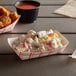 A table with a red check paper food tray holding chicken, potato salad, and fries.