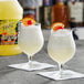 Two glasses of sweet and sour drinks with oranges and cherries.