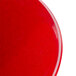 A close up of a red slanted melamine bowl with small black dots on the surface.
