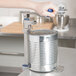 A person's hand using an Edlund commercial can opener to open a can.