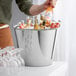 A man pouring drinks into a Vollrath stainless steel dairy bucket.