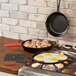 A Lodge cast iron skillet with eggs and bacon on a stove.