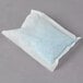 A white Urnex packet with blue powder inside.