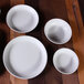 a group of white bowls on a wood surface