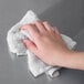 A hand wipes stainless steel with a white towel.