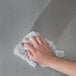 A hand holding a white towel cleaning stainless steel.