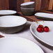 A table set with Elite Global Solutions Kona speckled white and chocolate bowls and a plate of cherries.