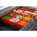 A Tablecraft red cast aluminum bowl with food in it on a counter.