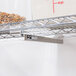 A Metro Super Erecta metal shelf with an adjustable undershelf slide holding a container of food.