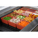 A Tablecraft copper cast aluminum bowl filled with food on a counter in a salad bar.