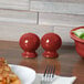 A table set with Fiesta Scarlet China salt and pepper shakers, a bowl, and a plate of pizza.