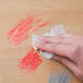 A hand using a Goo Gone Clean Up Wipe to clean a table.