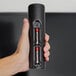 A hand holding a black Rayovac battery charger with four Rayovac Fusion AAA batteries inside.