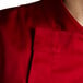 A close up of a Chef Revival tomato red chef jacket with short sleeves and hidden snap buttons.