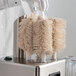 A person in white gloves uses a Noble Products glass washing machine.