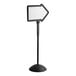 A white sign with a black border and a white arrow on a black stand.