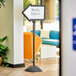 A Safco double sided magnetic/dry erase arrow sign with a black frame on a white surface.