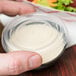 A hand using a Solo plastic lid to cover a portion cup of salad.