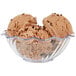 A clear tulip bowl with three scoops of chocolate ice cream.