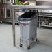 A grey Rubbermaid Slim Jim trash can under a counter.