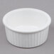 A Tuxton white fluted ceramic ramekin on a gray surface.