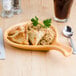 A Tuxton fry pan server with a plate of food and a spoon on a table.