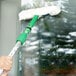 A person using a Unger green and white StripWasher to clean a window.