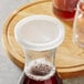 A Libbey plastic carafe with a clear lid on a table with a glass of red liquid.