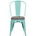A mint green metal chair with a wood seat.