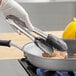 A person using Vollrath Jacob's Pride cooking tongs to cook food in a pan.