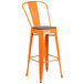 An orange bar stool with a wood seat.