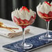 a glass of dessert with strawberries and whipped cream